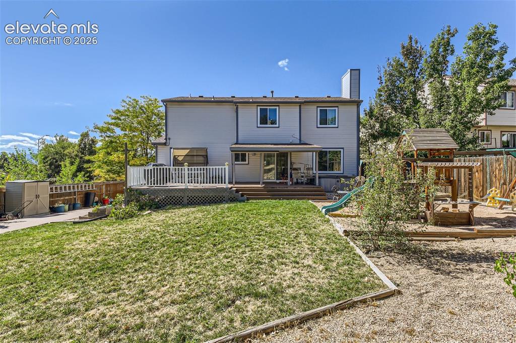 Image 41 of 49: Expansive backyard featuring a tiered wood deck, a sloped lawn, and a separ