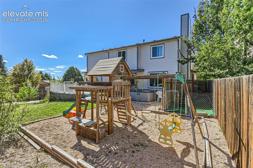 Image 43 of 49: Fenced backyard featuring a wood play structure, a hot tub, and a raised co