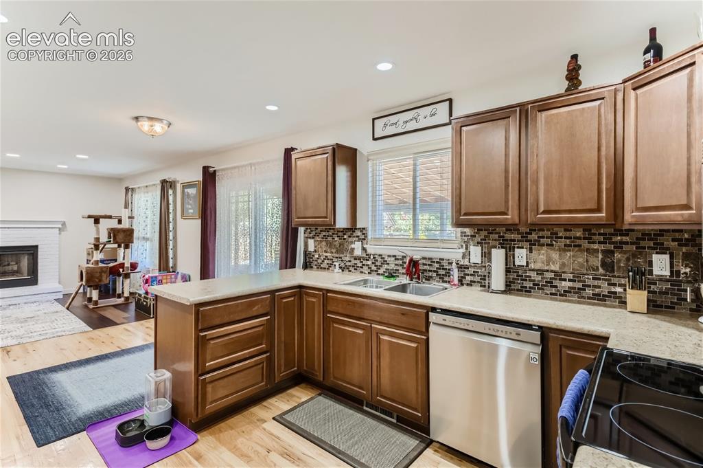 Image 9 of 49: Kitchen featuring wood-finish cabinetry, stainless steel dishwasher, tile b