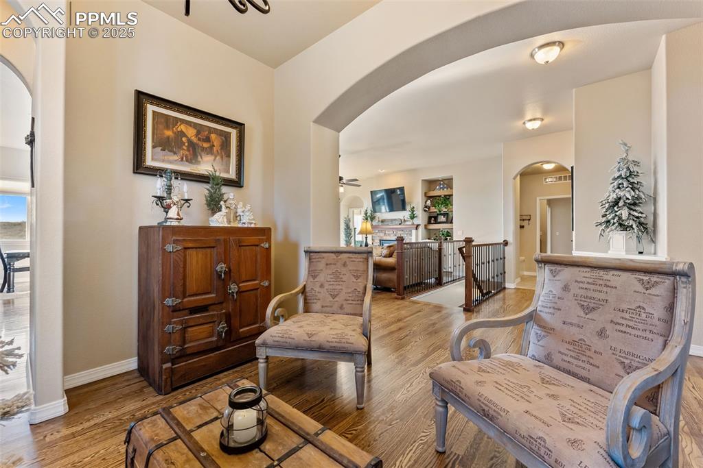 Image 12 of 50: Dining room with arched walkways, hardwood floors, and an upstairs landing
