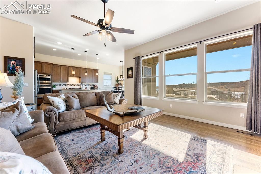 Image 17 of 50: Living area with ceiling fan, hardwood flooring, and recessed lighting