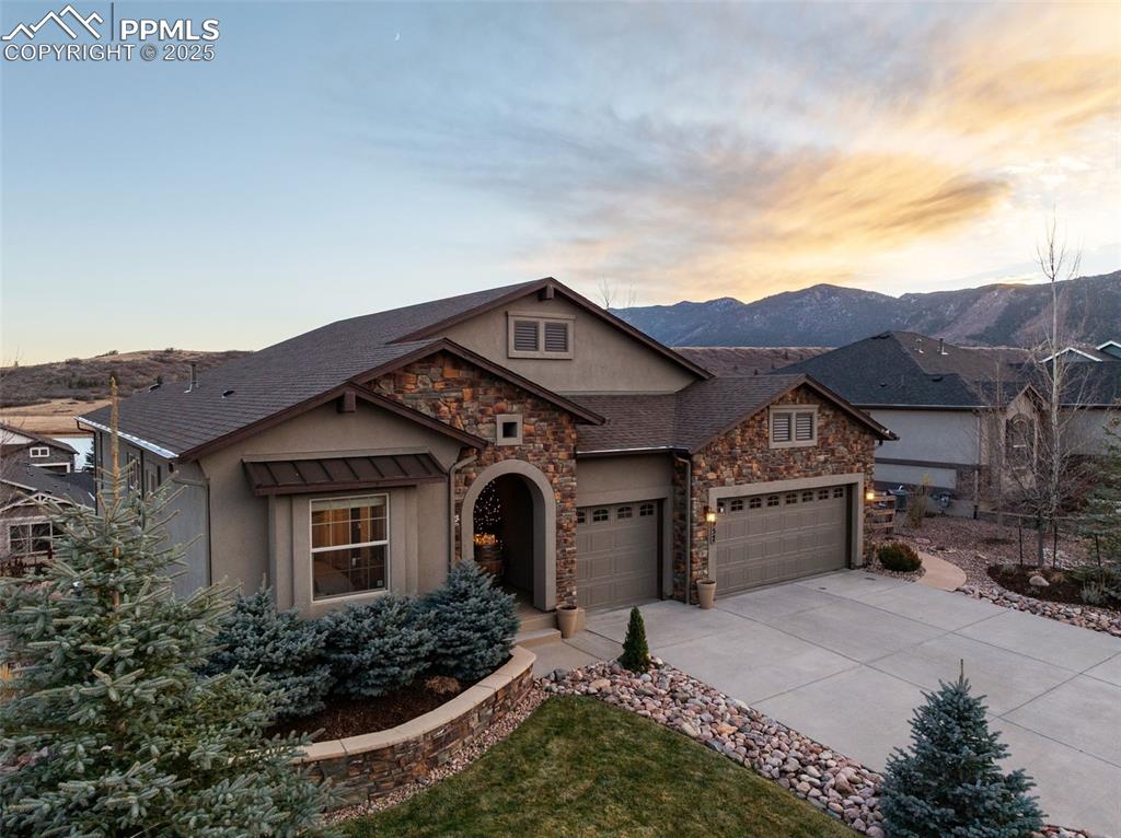 Image 2 of 50: Craftsman-style home featuring stone siding, stucco siding, concrete drivew