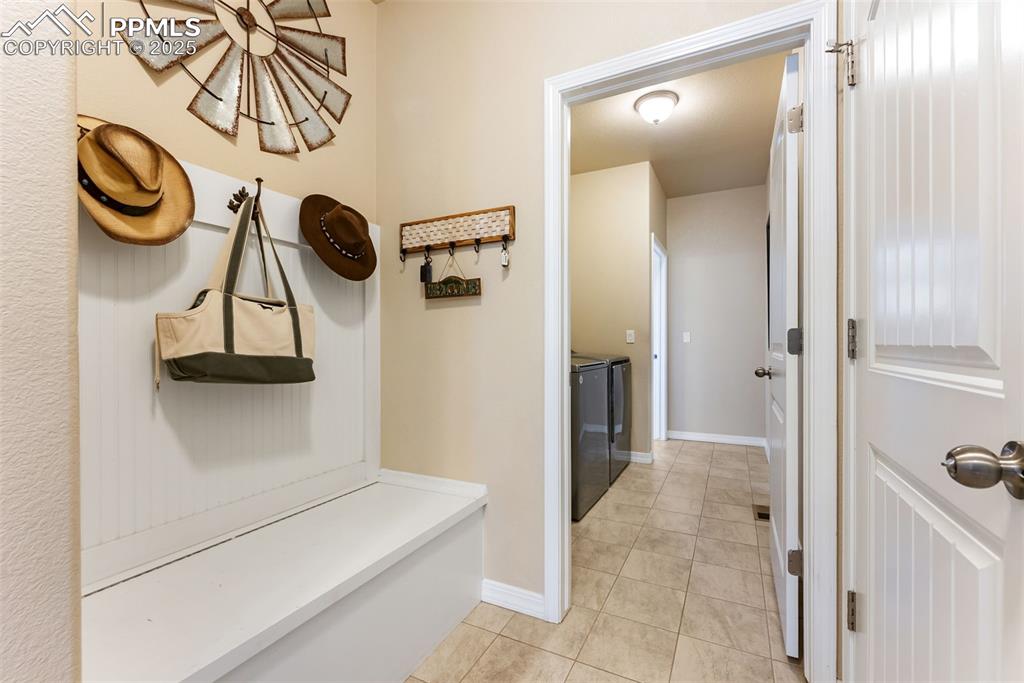 Image 25 of 50: Mudroom featuring drop zone with bench, storage, hooks