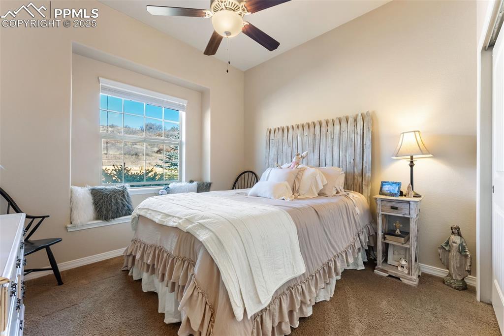 Image 26 of 50: Secondary main level bedroom featuring carpet flooring and a ceiling fan. C