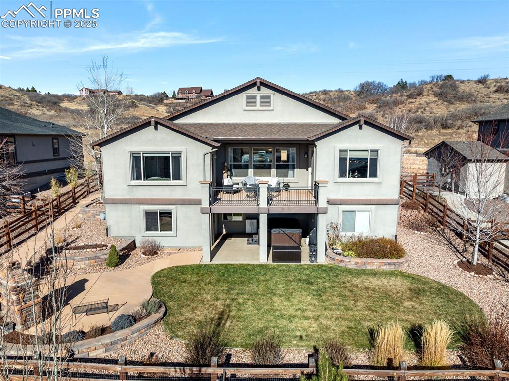 Image 44 of 50: Back of house featuring a fenced backyard, stucco siding, a balcony, and a