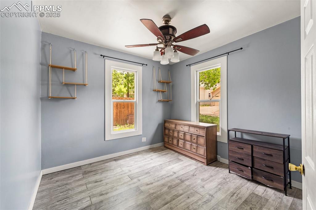 Image 22 of 48: Cozy bedroom with ceiling fan and large window.