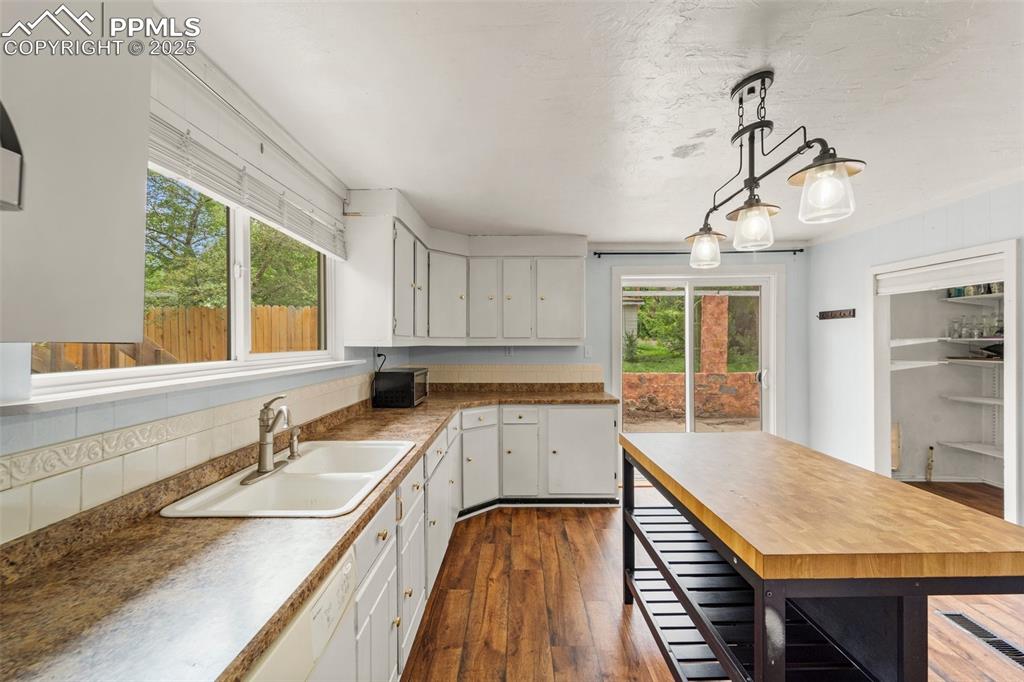 Image 30 of 48: Bright kitchen with white cabinetry and wood accents.