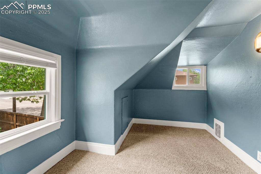 Image 40 of 48: Upper-level bonus area or playroom with angled ceiling.