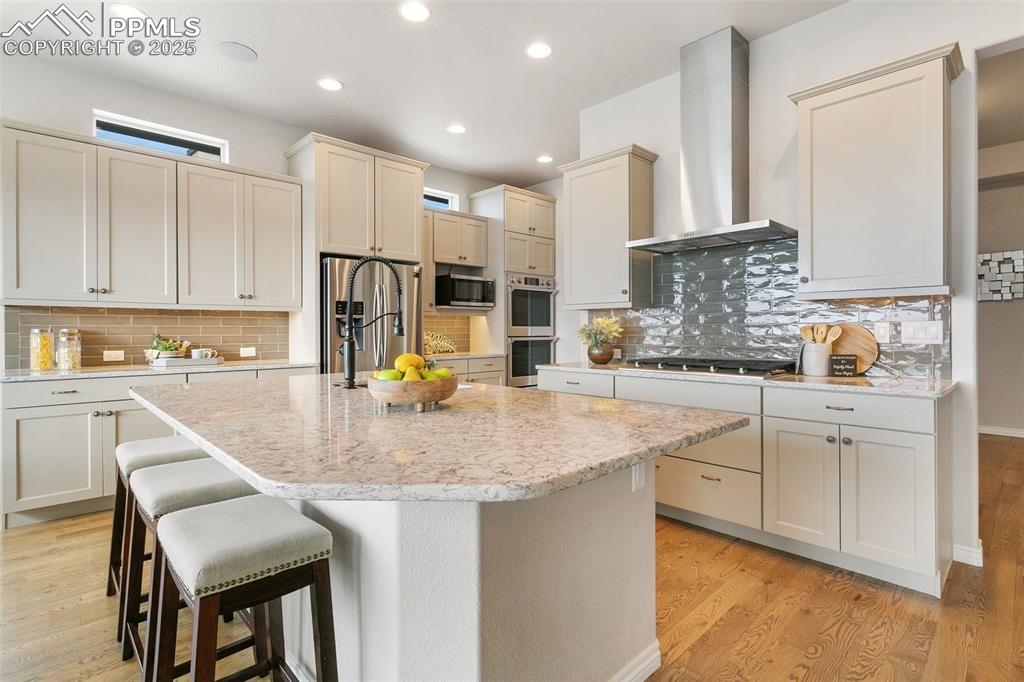 Image 11 of 41: Kitchen featuring wall chimney exhaust hood, stainless steel appliances, ta