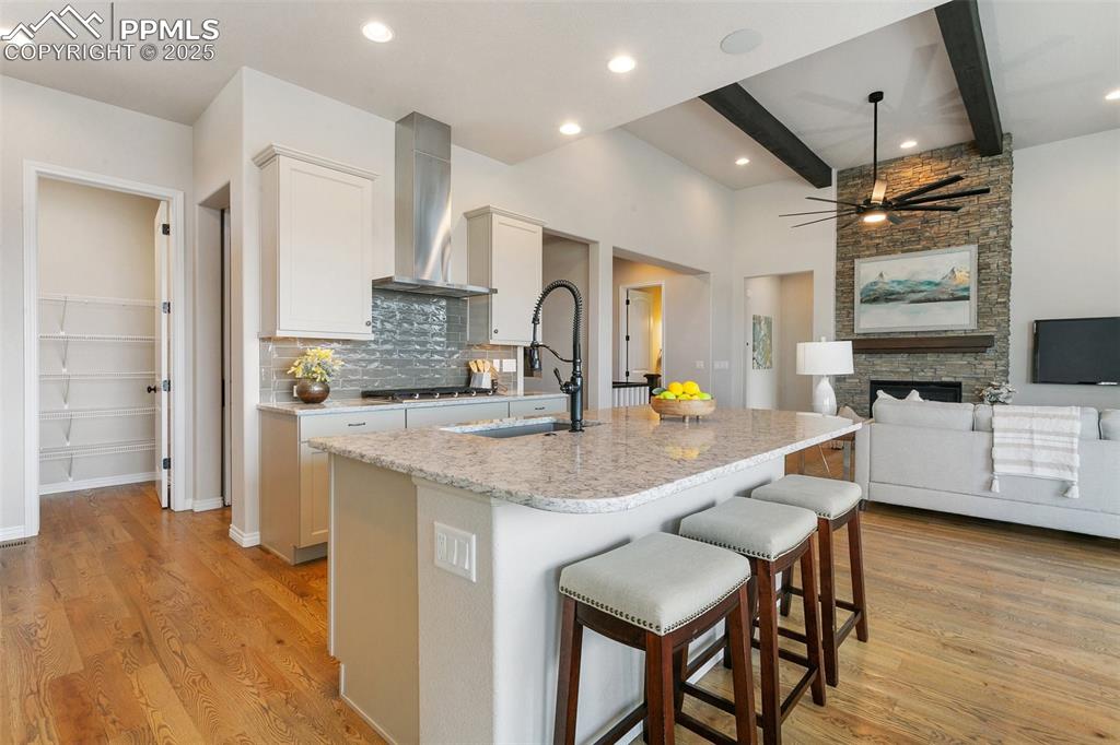 Image 13 of 41: Kitchen with wall chimney exhaust hood, tasteful backsplash, beamed ceiling