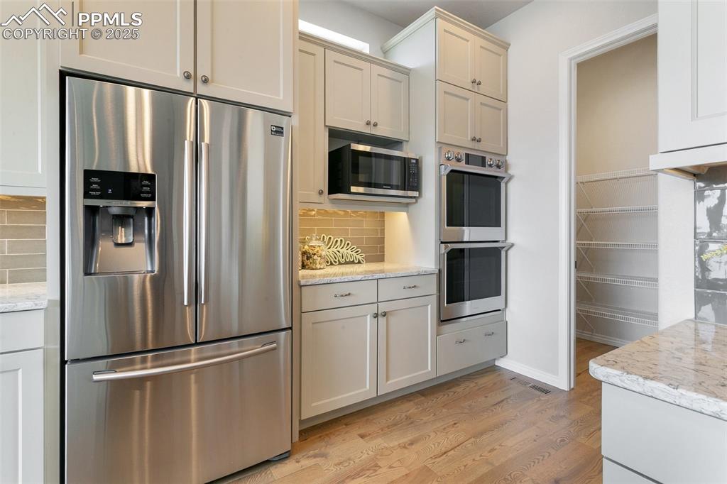Image 14 of 41: Kitchen with stainless steel appliances, light wood-style flooring, backspl