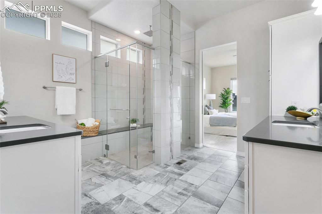 Image 18 of 41: Bathroom featuring double vanity, a stall shower, ensuite bathroom, and mar