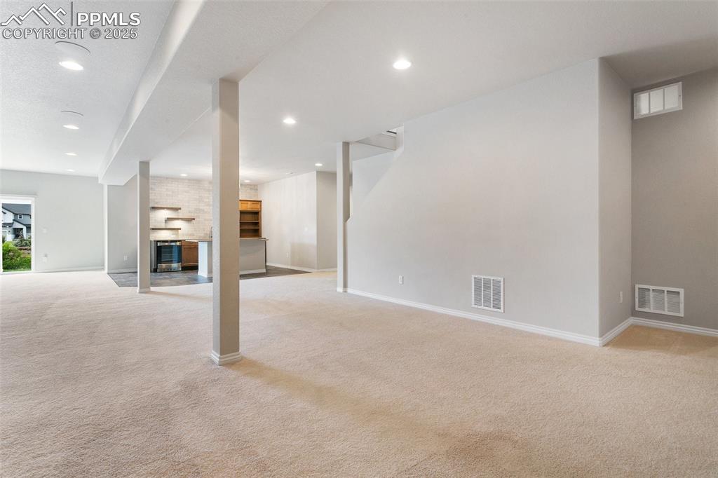 Image 22 of 41: Unfurnished living room with light carpet, a brick fireplace, beverage cool