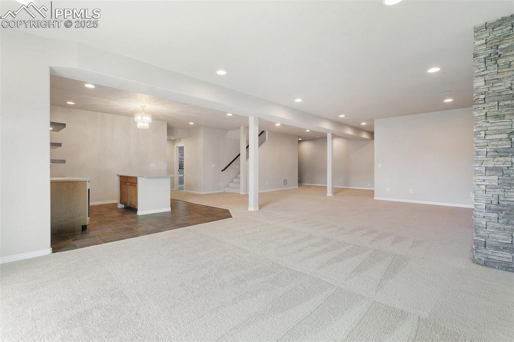 Image 24 of 41: Finished basement with light carpet, recessed lighting, and stairway