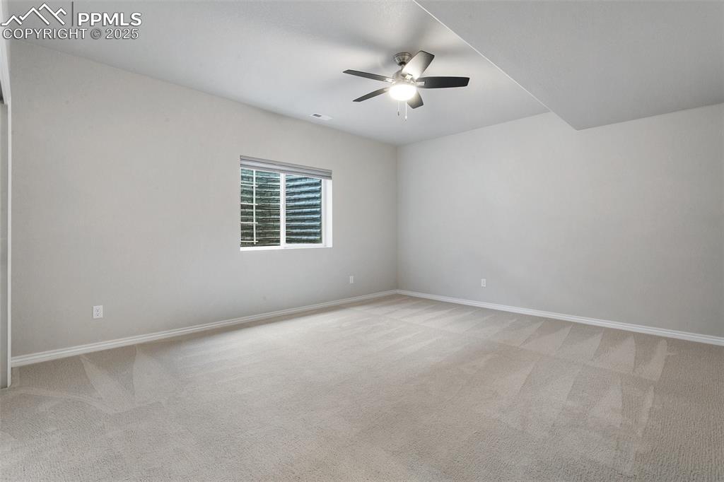 Image 28 of 41: Empty room with ceiling fan and light colored carpet