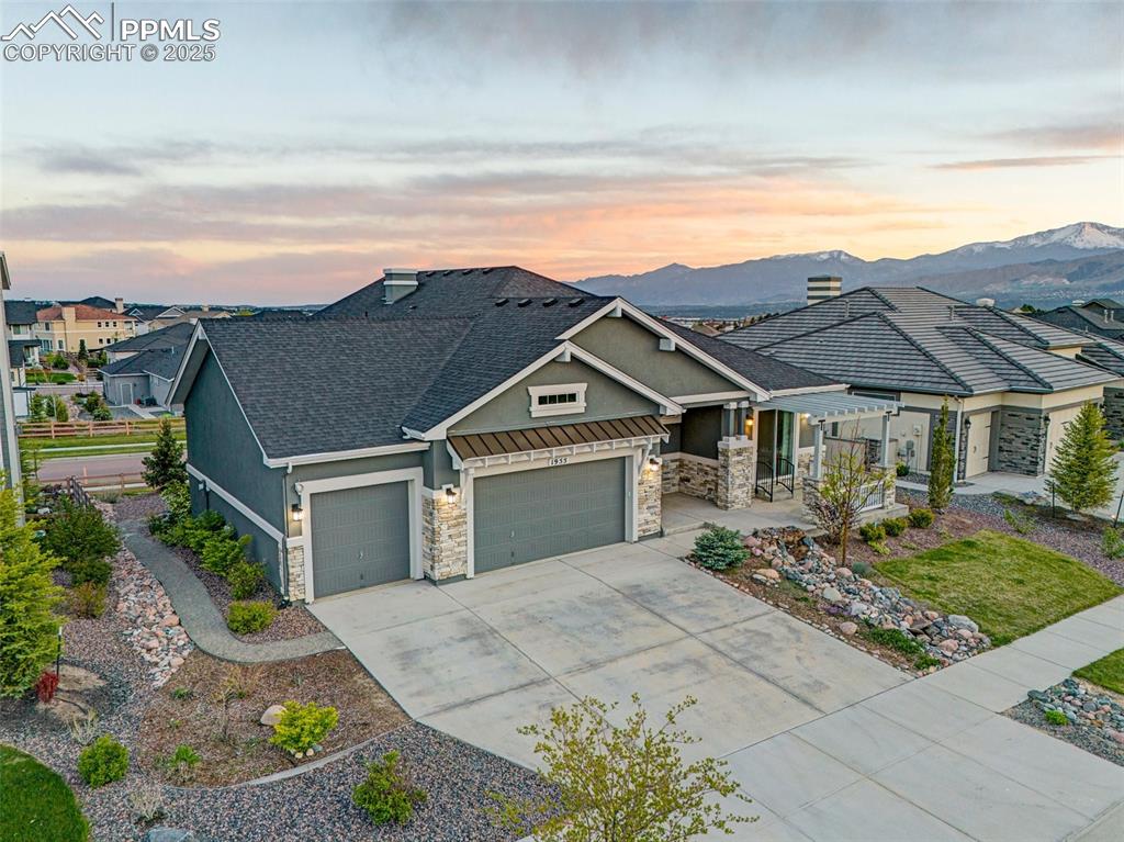 Image 3 of 41: Craftsman-style house featuring stone siding, an attached garage, stucco si