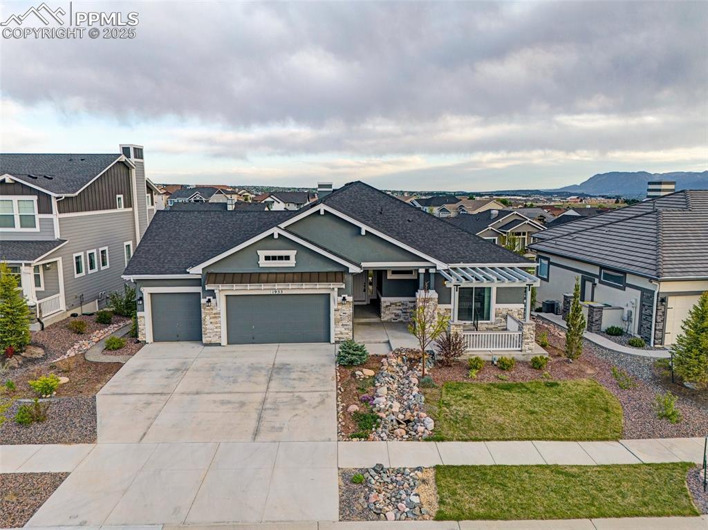 Image 39 of 41: View of front of property with a garage, stone siding, and roof with shingl