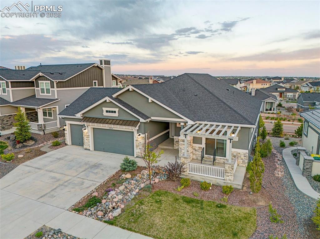 Image 40 of 41: Craftsman-style home with stone siding, roof with shingles, a garage, and c
