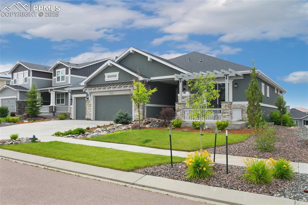 Image 41 of 41: Craftsman inspired home with stone siding, a front lawn, driveway, and a po