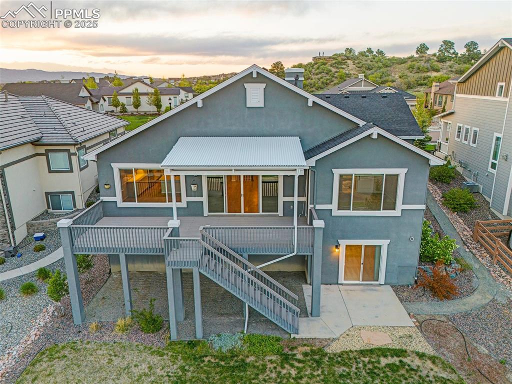 Image 5 of 41: Back of house at dusk with stucco siding, a patio, stairs, a wooden deck, a