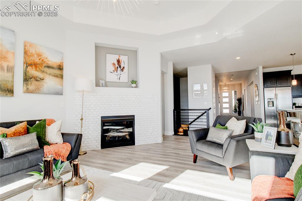 Image 11 of 30: Living room featuring a tray ceiling, light wood-style flooring, and recess