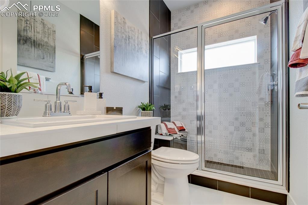 Image 13 of 30: Bathroom with vanity, toilet, and a shower stall
