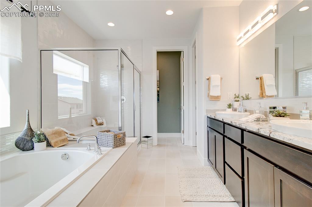 Image 16 of 30: Bathroom with a stall shower, a garden tub, double vanity, tile patterned f