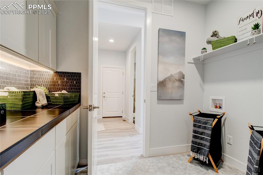 Image 18 of 30: Laundry room with washer hookup, baseboards, cabinet space, and recessed li