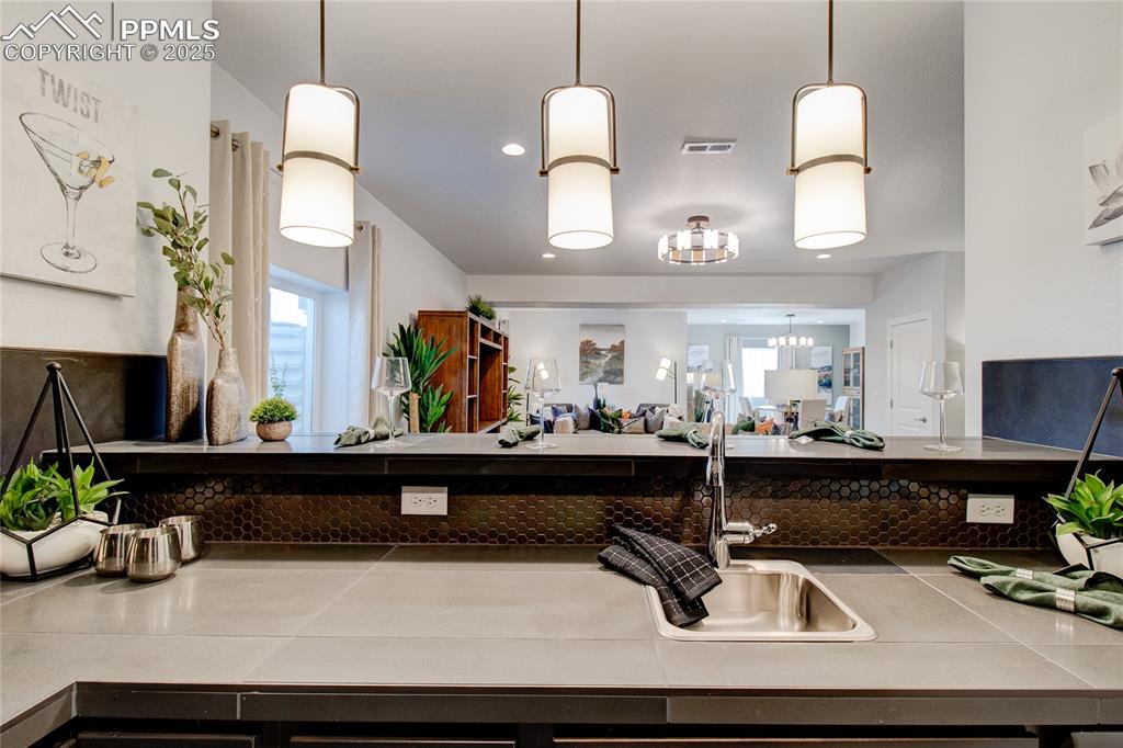 Image 24 of 30: Kitchen with a sink, a chandelier, tile counters, and hanging light fixture