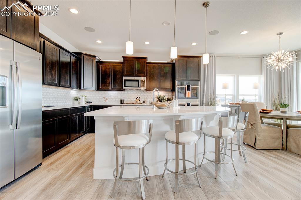 Image 6 of 30: Kitchen featuring stainless steel appliances, light wood-style flooring, de