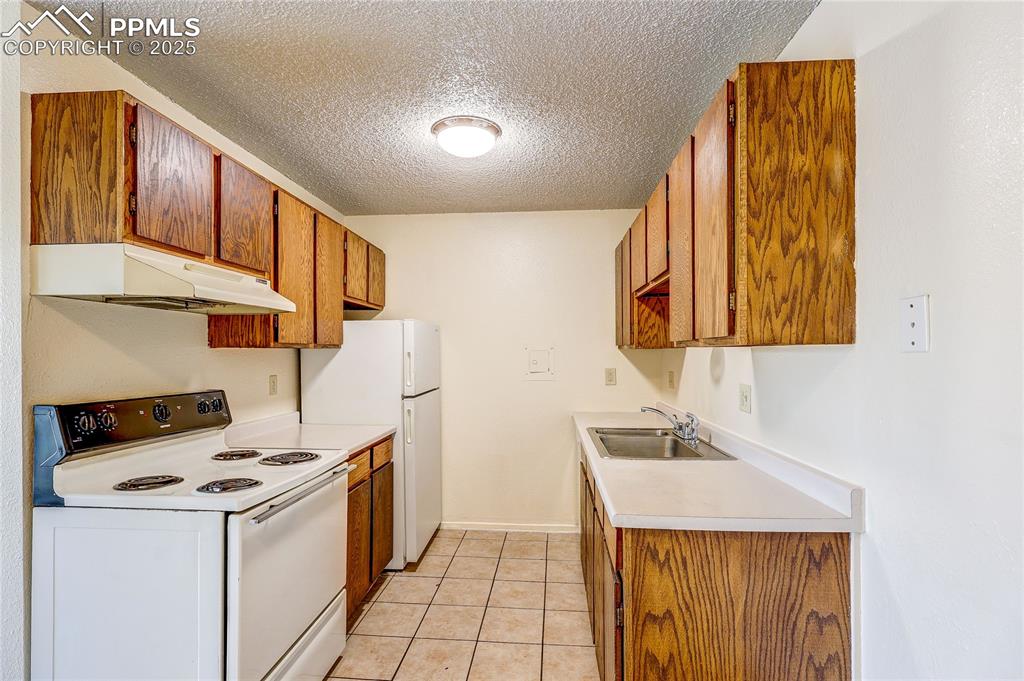 Image 6 of 20: Kitchen with white appliances, under cabinet range hood, a textured ceiling