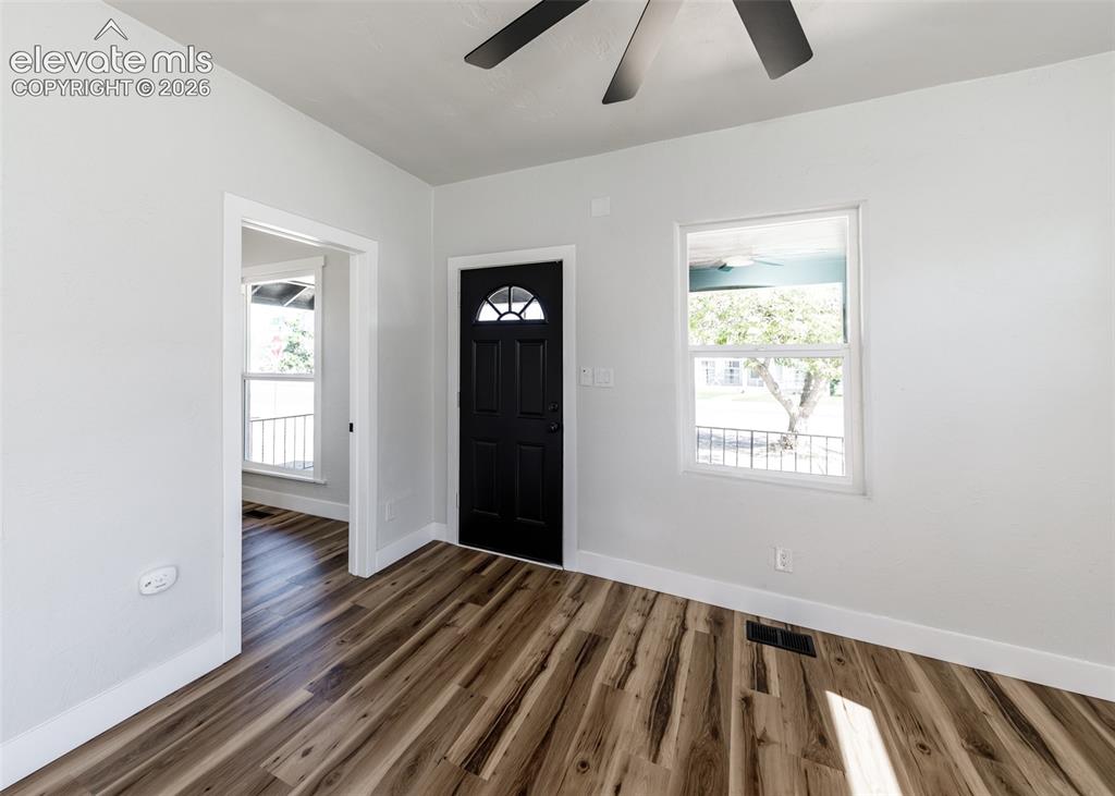 Image 3 of 33: Neutral-toned interior featuring wood-finish flooring, a multi-paneled blac