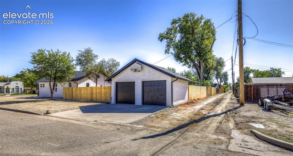 Image 31 of 33: Detached two-car garage featuring a stucco exterior, asphalt shingle roof, 