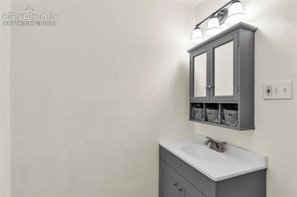 Image 17 of 29: Bathroom vanity featuring a grey cabinet, white countertop, and single basi