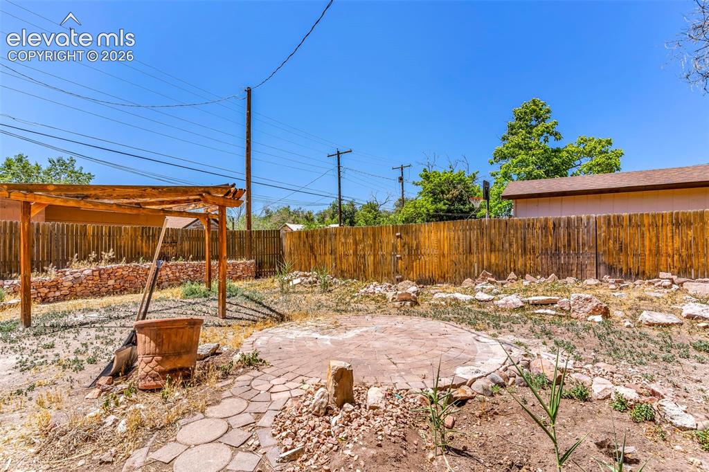 Image 25 of 29: Expansive backyard featuring a wood pergola, privacy fencing, a circular pa