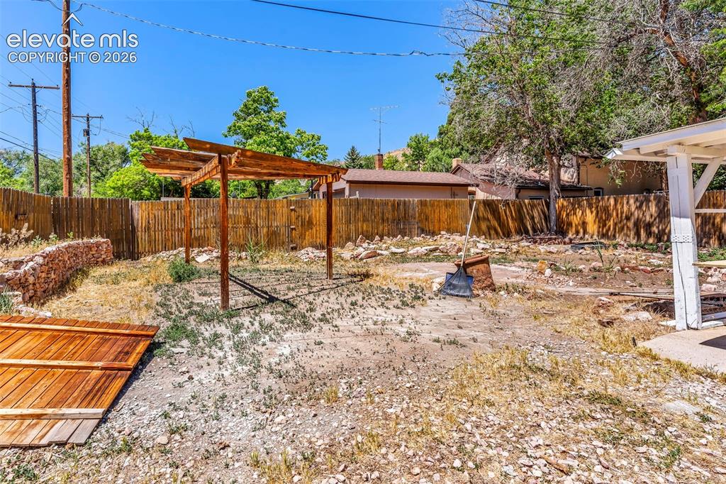 Image 26 of 29: Expansive backyard featuring a wood pergola structure, privacy fencing, a p