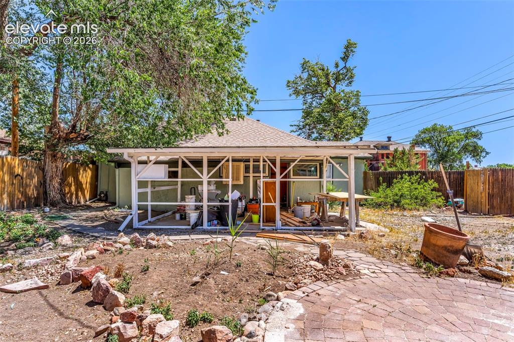Image 27 of 29: Brick paver patio with a rock garden accent, mature trees providing natural