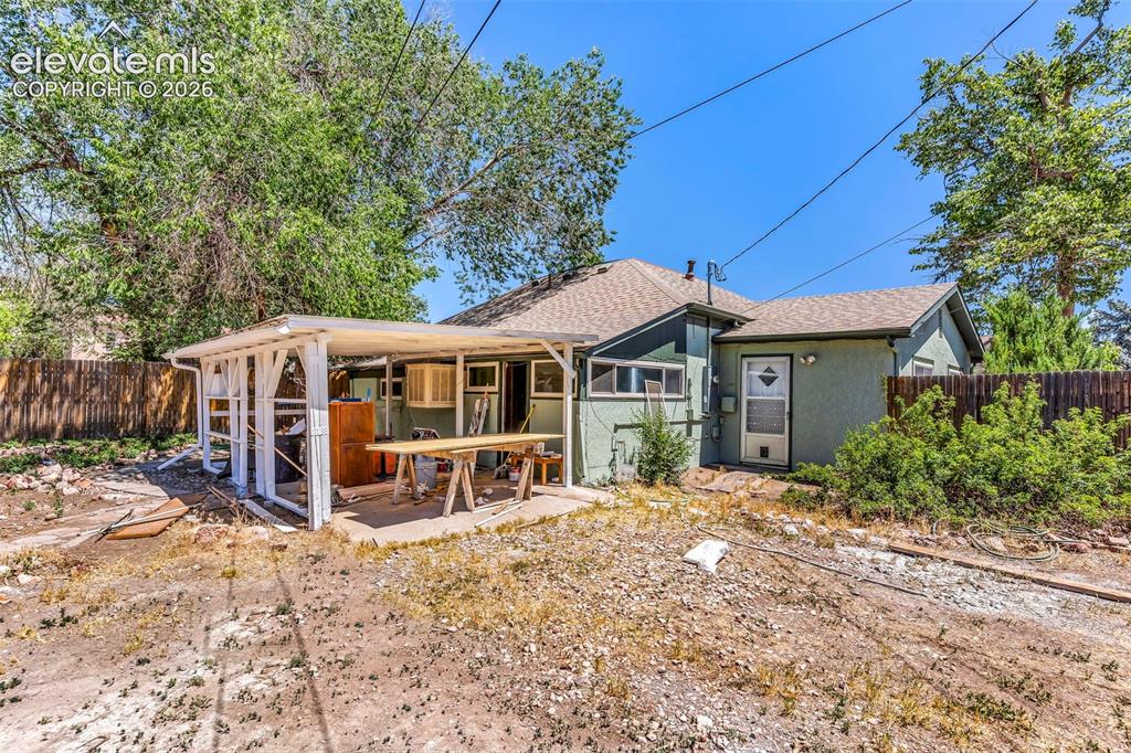 Image 28 of 29: Rear exterior featuring a covered patio structure, stucco siding, and a gab