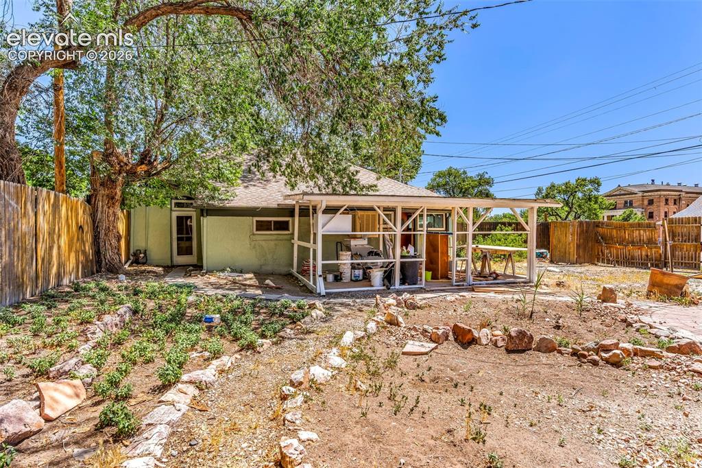 Image 29 of 29: Expansive backyard featuring a covered patio, a privacy fence, and mature t