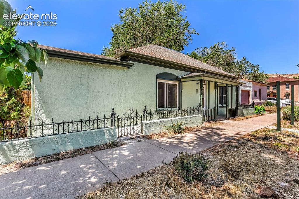 Image 4 of 29: Stucco exterior with a covered front porch featuring decorative columns
