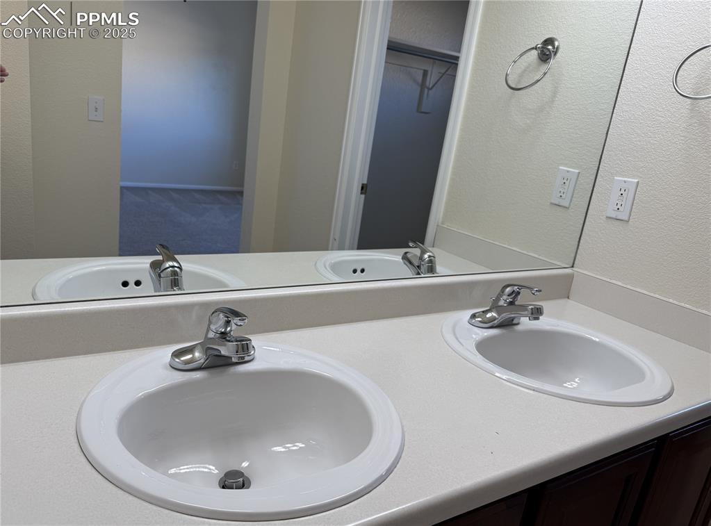 Image 14 of 32: Full bathroom featuring a textured wall, double vanity, and a spacious clos