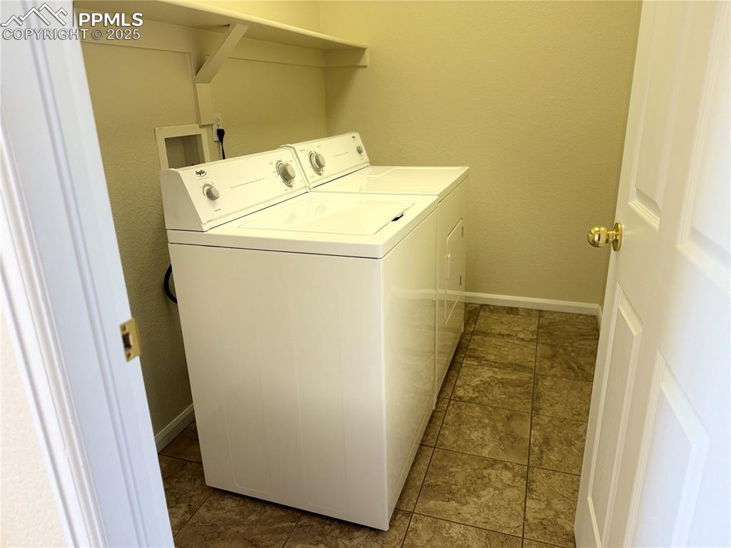 Image 18 of 32: Washroom with washer and clothes dryer, a textured wall, and light tile pat