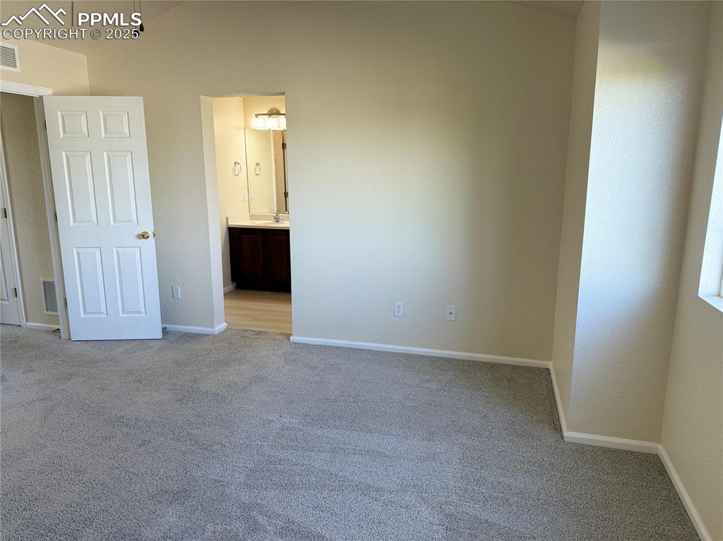 Image 22 of 32: Unfurnished bedroom with light carpet and ensuite bathroom