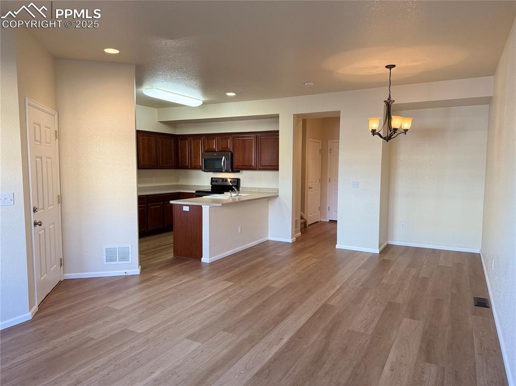 Image 3 of 32: Kitchen featuring light countertops, light wood finished floors, a peninsul
