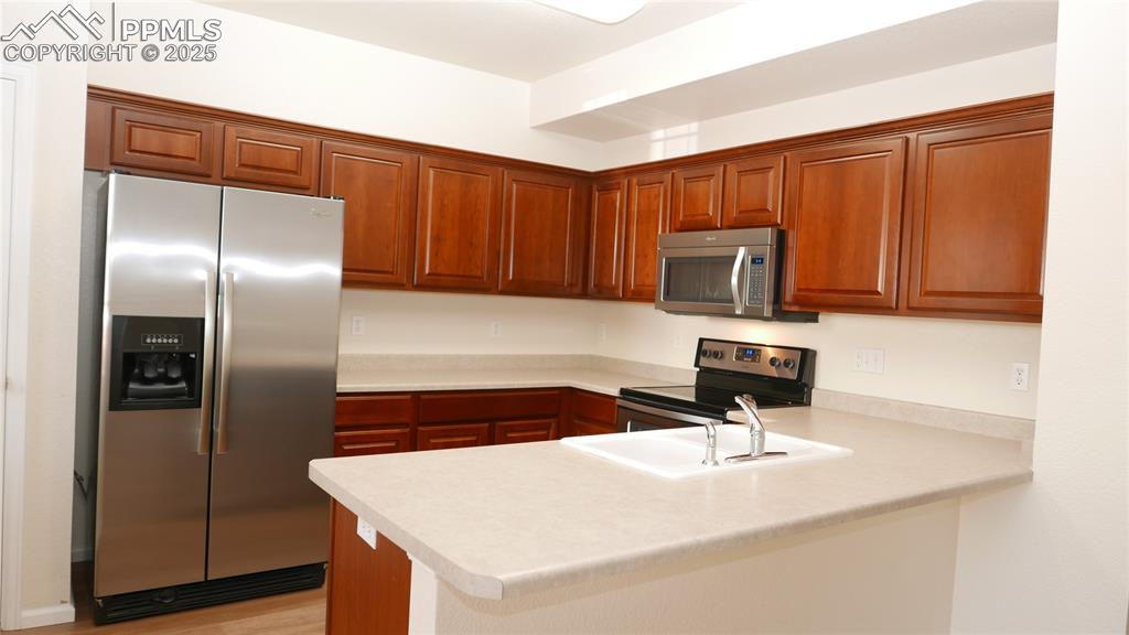 Image 4 of 32: Kitchen featuring appliances with stainless steel finishes, light counterto