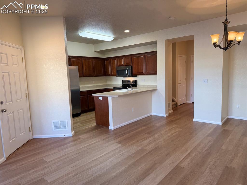Image 5 of 32: Kitchen with light countertops, a peninsula, light wood-style flooring, sta