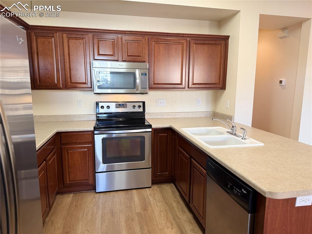 Image 6 of 32: Kitchen featuring stainless steel appliances, a peninsula, light wood-type