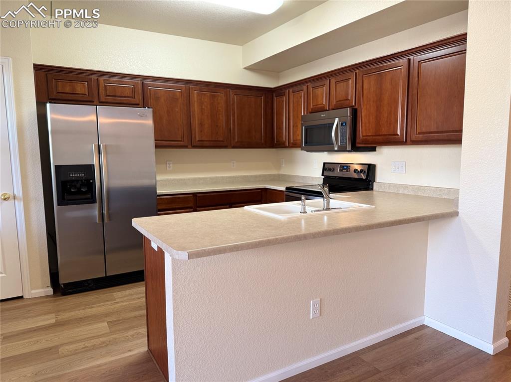 Image 8 of 32: Kitchen with appliances with stainless steel finishes, light countertops, l