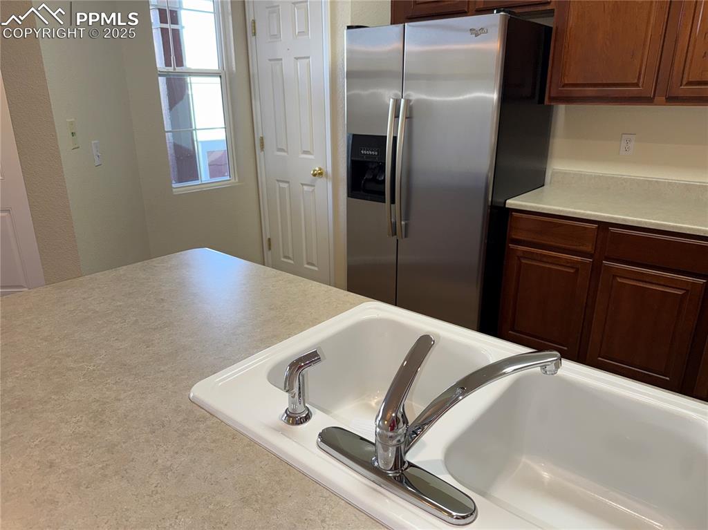 Image 9 of 32: Kitchen with stainless steel fridge with ice dispenser, light countertops,