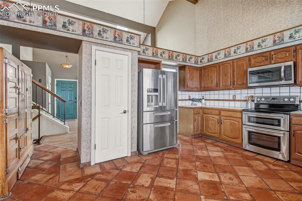 Image 4 of 35: Stainless steel appliances and beautiful tile floors stretching from wall t